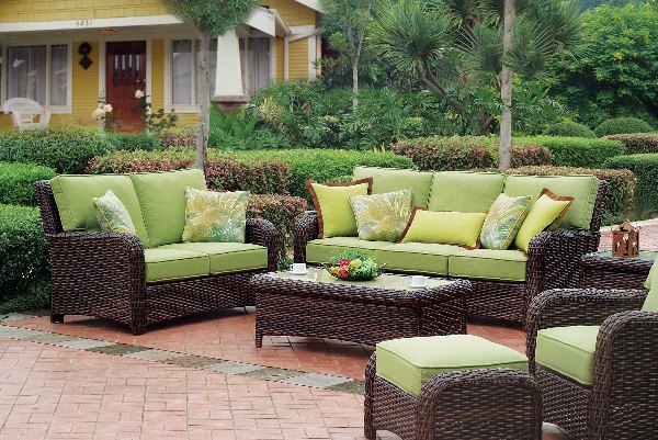 Bộ sofa mây nhựa với đệm xanh lá cây tạo điểm nhấn thư giãn cho khu vực chuyển tiếp ngoài trời, kết nối hài hòa giữa nhà và vườn.